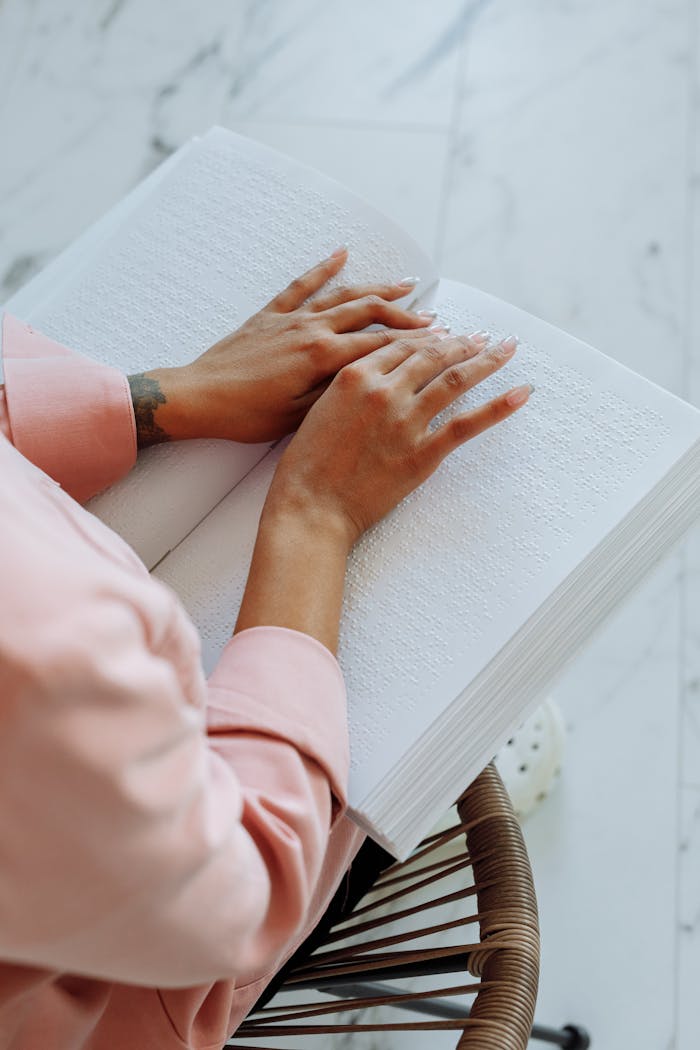 our-services-2 Close-up of hands reading a Braille book, symbolizing accessibility for the visually impaired.